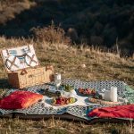 Въже за пикник с кошница и храна, зеленина и планински пейзаж, релаксираща атмосфера, туристически приключения, екотуризъм България.