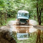 търговски бус преминава през кална пътека в горска местност, приключение в природата, България.